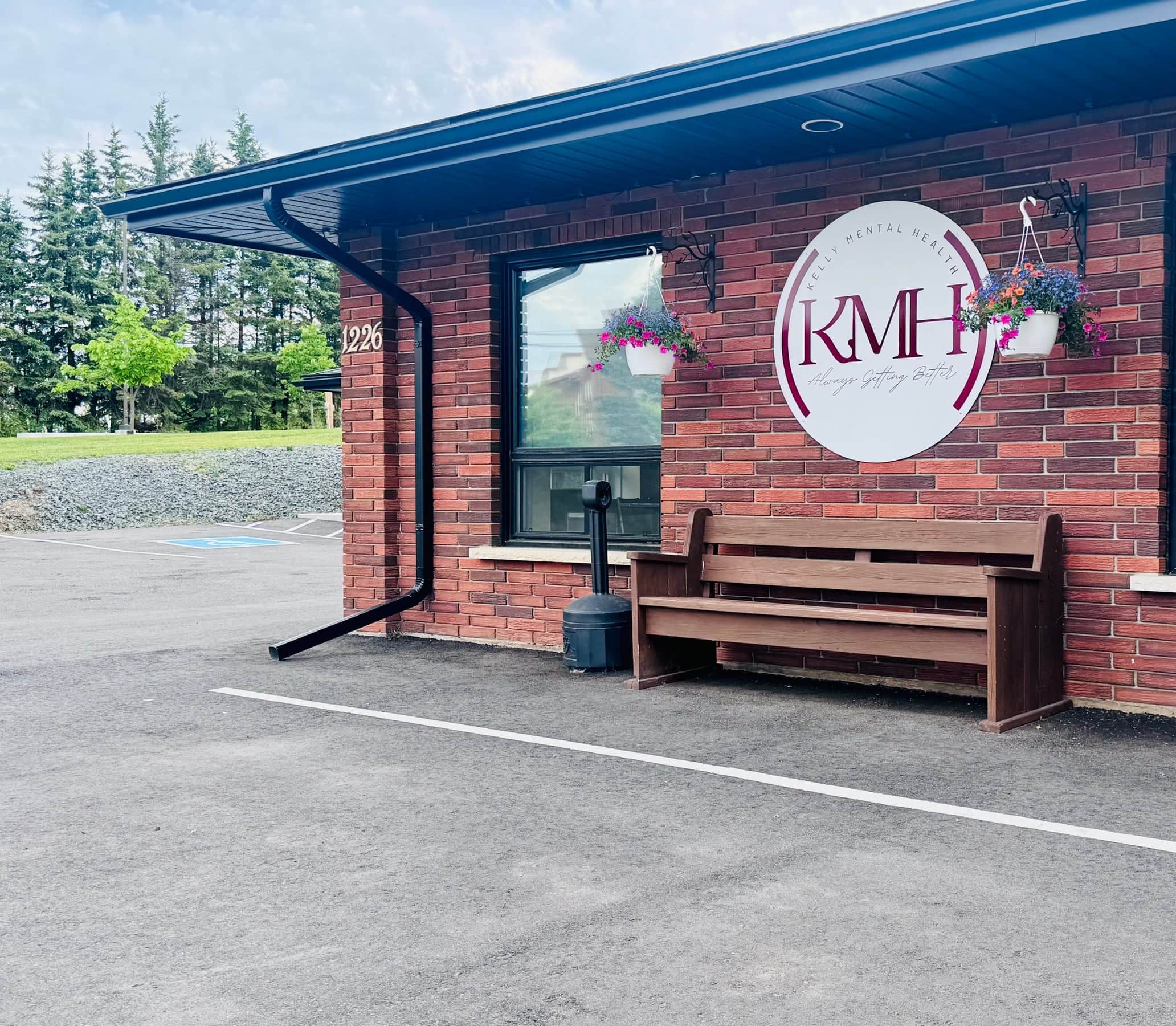 The Cottage on Dawson with bench, hanging baskets, and the Kelly Mental Health window sign